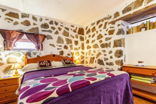 ein Schlafzimmer mit einem Bett mit einer Steinwand in der Unterkunft La Fortaleza - Casa La Fuentita in El Charco