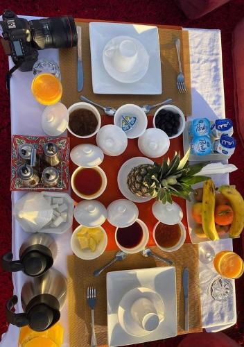 een tafel met borden en kommen met voedsel bij Elysium Dunes Camp in Merzouga