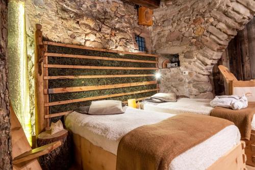 two beds in a room with a stone wall at Ansitz Gurtenhof - Andreas Hofer in Tesimo