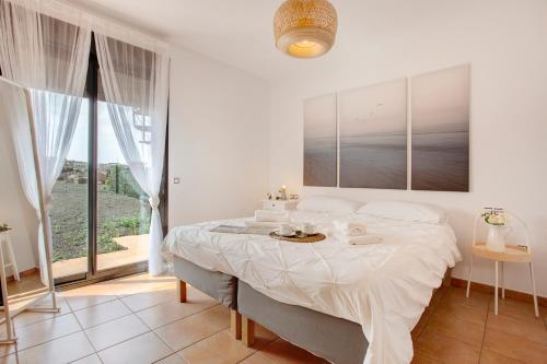 a white bedroom with a large bed and a window at Villa Norteventura in Majanicho