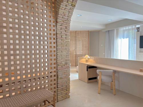 Cette chambre dispose d'un bureau et d'une chaise à côté d'un mur en briques. dans l'établissement Les Clarisses Boutique Hotel, à Vic