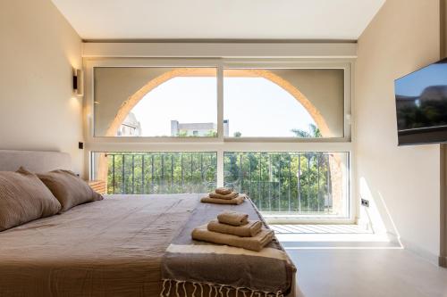 a bedroom with a large window with towels on a bed at Casa Eva in Estepona