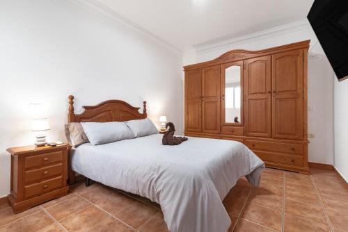 a bedroom with a large bed and a wooden cabinet at One Life One Dream Gran Canaria in Carrizal