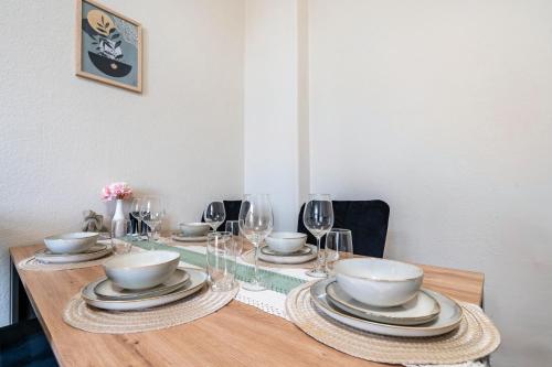 a wooden table with plates and bowls and wine glasses at Bahnhofsnahes Altstadt-Paradies in Cottbus