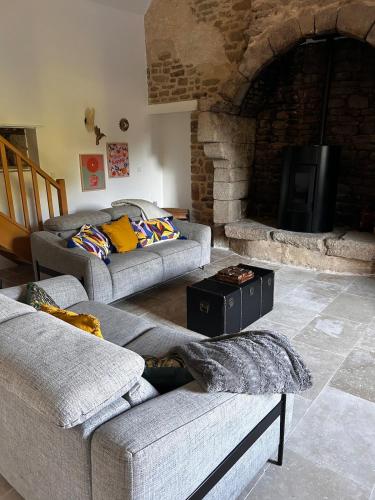 a living room with two couches and a stone fireplace at L'annexe in Plumelec