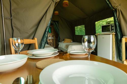 ein Tisch mit Tellern und Weingläsern in einem Zelt in der Unterkunft Safari Glamping Portugal Flamingo in Ventosa