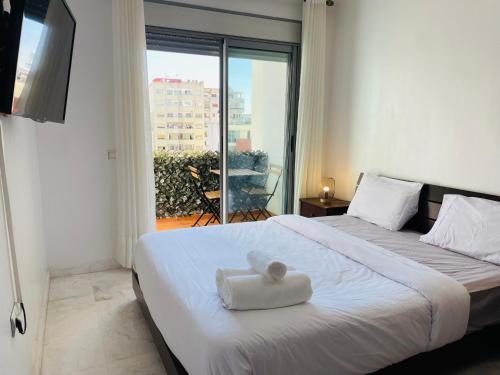 a bedroom with a bed with a white towel on it at Jolie appt avec Balcon - Hypercentre, proche Medina et Plage in Tangier