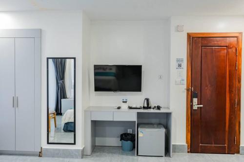 Habitación con escritorio, TV y espejo. en Jason Residencia One Hotel, en Phnom Penh