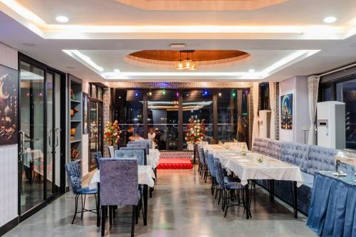 Un comedor con mesas y sillas blancas. en Jason Residencia One Hotel, en Phnom Penh