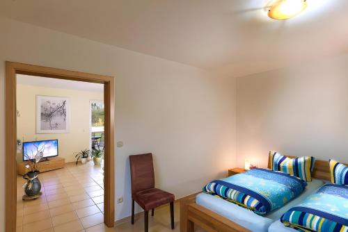een slaapkamer met een bed, een stoel en een televisie bij Apartment Kessy in Fuhlendorf