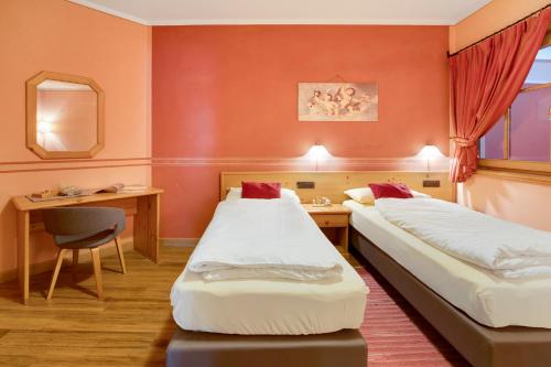ein Hotelzimmer mit zwei Betten und einem Schreibtisch in der Unterkunft Alba Villa Nordica in Livigno