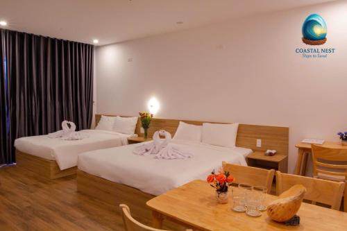 a hotel room with two beds and a table at Coastal Nest - Steps to Sand in Danang