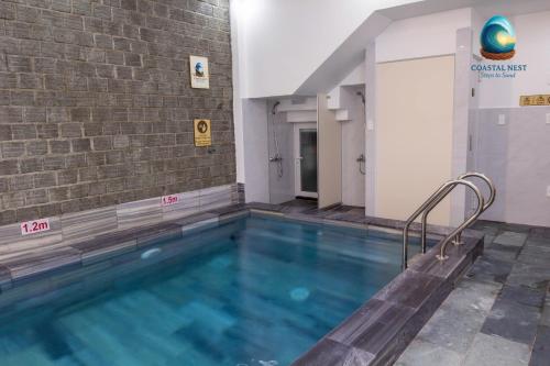 een zwembad in een gebouw met een bakstenen muur bij Coastal Nest - Steps to Sand in Da Nang