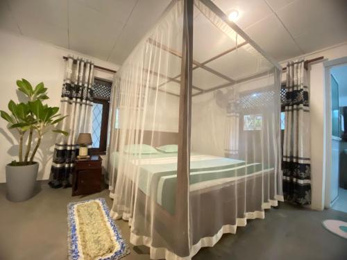 sypialnia z łóżkiem z baldachimem i zasłonami w obiekcie Surfing Lion Villa Hiriketiya w mieście Dickwella