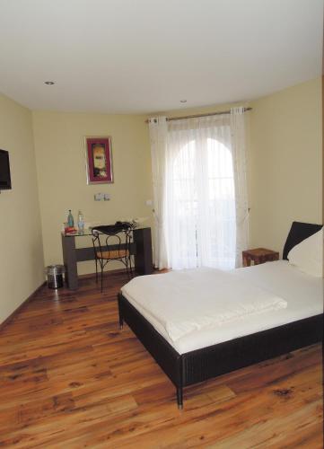 a bedroom with a bed and a table and a window at Hostellerie Bacher in Neunkirchen
