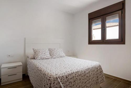 une chambre blanche avec un lit et une fenêtre dans l'établissement Casa La Teja 2 - Solo Familias, à Vejer de la Frontera