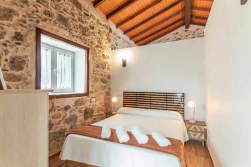 een slaapkamer met een bed met een stenen muur bij Casa Eloisa in Teror