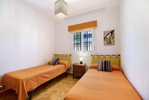 ein Zimmer mit zwei Betten und einem Fenster in der Unterkunft Chalet con piscina en la Barrosa in Chiclana de la Frontera