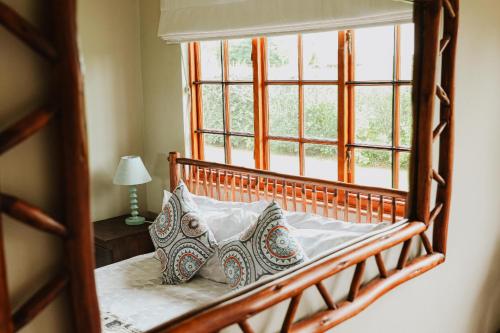 Bett mit Kissen in einem Zimmer mit Fenster in der Unterkunft Cicada Cottage Peaceful Drakensberg Retreat in Underberg
