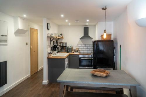 a kitchen with a table and a sink and a refrigerator at Mor Ki -A perfectly situated modern flat in Looe in Looe