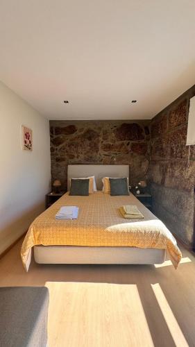 a bedroom with a large bed with a stone wall at Bernardes House in Castelo de Paiva