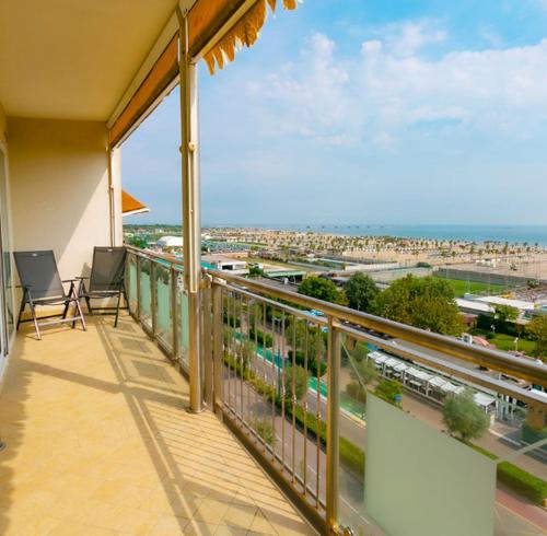 a balcony with two chairs and a view of a city at Le Murrine Frontemare Apartment Sea View 503 in Sottomarina