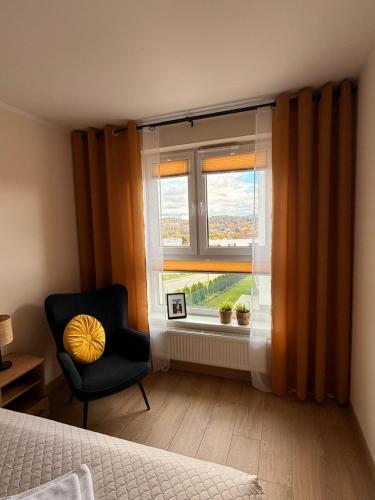 a bedroom with a chair and a window at M&D apartamenty w Karkonoszach! 2 sypialnie, salon z aneksem, balkon z widokiem na góry in Jelenia Góra