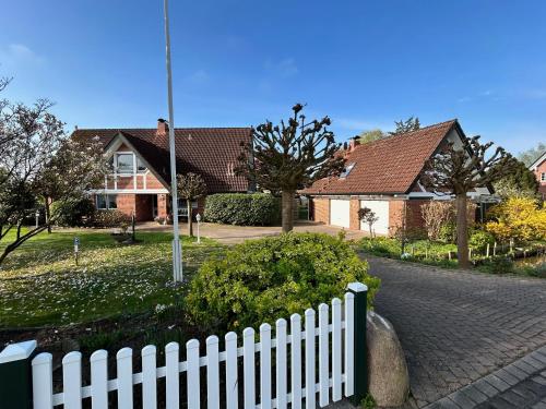une clôture blanche devant une maison dans l'établissement Ferienwohnungen Altes Land I Jork-Borstel, à Jork