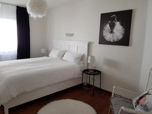 a bedroom with a white bed and a chair at Auszeit Am Wildkatzenpfad in Bad Herrenalb