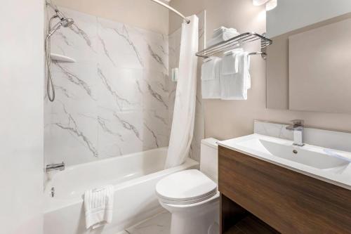 a white bathroom with a toilet and a sink at Econo Lodge in Montréal