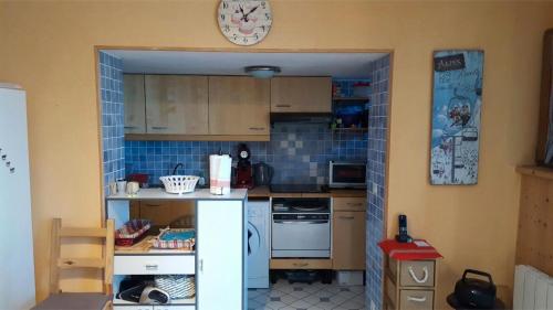 a small kitchen with a counter and a clock on the wall at Appartement plein ciel 4-6 pers in Allevard