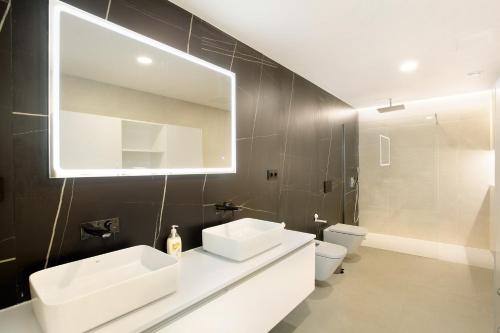 a bathroom with two sinks and a mirror and a toilet at Penthouse Sun beach best view in Las Palmas de Gran Canaria