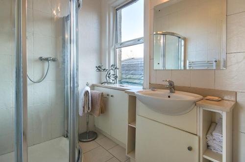 een badkamer met een wastafel, een douche en een spiegel bij Garrane House in Croom