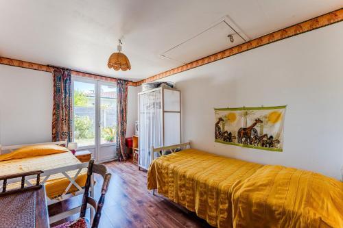 ein Schlafzimmer mit einem Bett mit gelber Tagesdecke in der Unterkunft Maison De Vacances Près Du Centre in La Teste-de-Buch