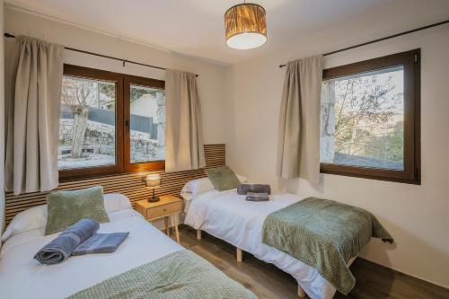 Dos camas en una habitación con dos ventanas. en El Nogal de Marieta, en Peguerinos