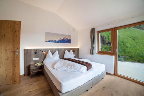 a bedroom with a bed and a large window at Flatschhof - Apartment Cevedale in Castelbello-ciardes