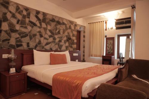 een hotelkamer met een bed en een stoel bij By The Bay Kovalam in Trivandrum