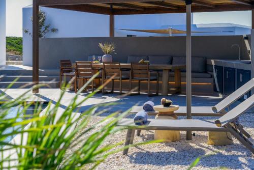 a patio with a couch and a table and chairs at ANOTERRA VILLAS -Auralis in Ambelas
