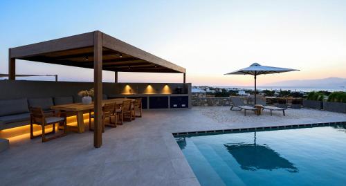 a patio with a table and an umbrella next to a pool at ANOTERRA VILLAS -Auralis in Ambelas