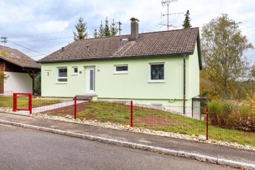 a white house with a red fence at Haus Wiesengrund - Hundefreundlich in Gammertingen