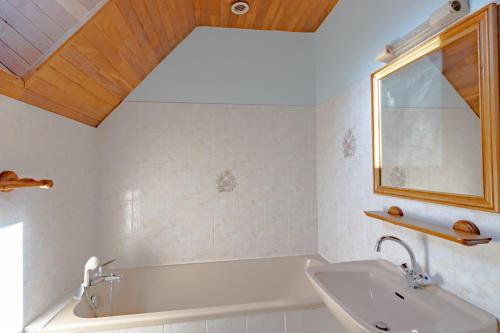 ein Badezimmer mit Badewanne, Waschbecken und Spiegel in der Unterkunft Le Petit Pech in Le Sirey