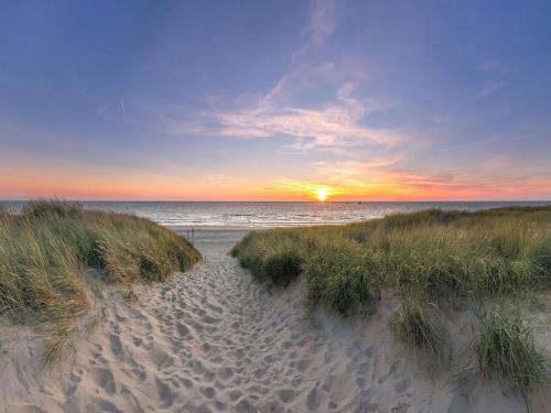 a sunset over a sandy beach with the ocean at Pretty Holiday Home in De Koog Texel with Garden in Westermient