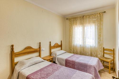 レスカラにあるApartamento la Siestaのベッド2台、窓、窓が備わる客室です。