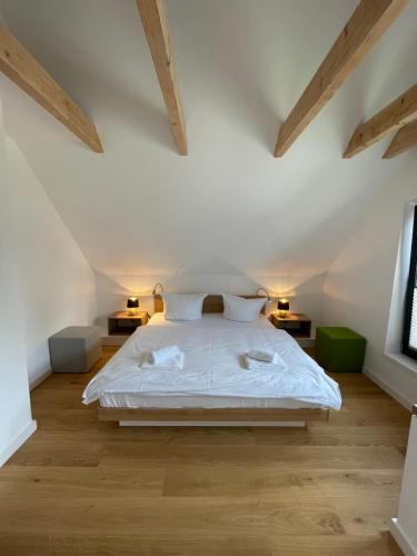 a bedroom with a bed with white sheets and wooden floors at SandKorn 1 und 2 in Pruchten