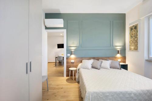 - une chambre avec un lit blanc et un mur bleu dans l'établissement Victoria Apartments Family, à Diano Marina