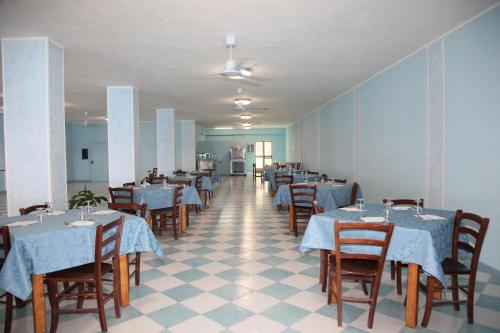 a dining room with tables and chairs with blue table cloth at Villaggio Camping La Scogliera in Ricadi