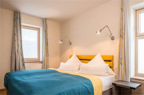 a bedroom with a bed with a blue blanket and two windows at Ferienwohnung Relaxx in Bad Endorf