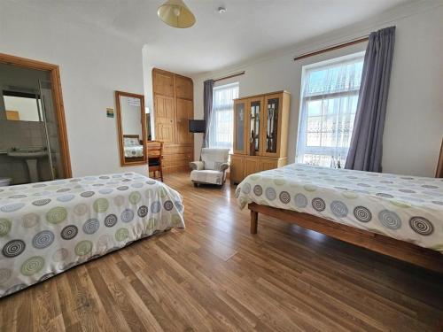 a bedroom with two beds and a chair in it at The Albert Hotel in Gloucestershire