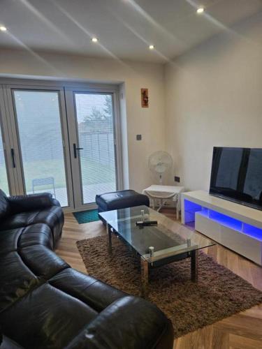 a living room with a leather couch and a coffee table at Reading Guest House in Reading