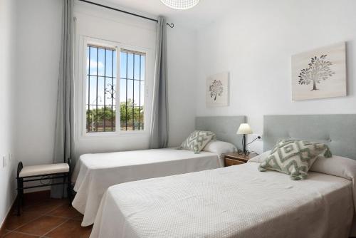 ein Schlafzimmer mit zwei Betten und einem Fenster in der Unterkunft Villa Juani Sólo familias in Roche